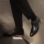 Image of a man walking up stairs in black pants and a black pair of designer men's shoes