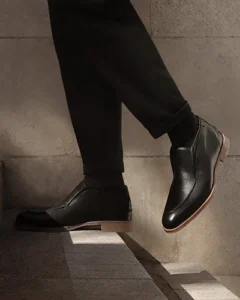 Image of a man walking up stairs in black pants and a black pair of designer men's shoes
