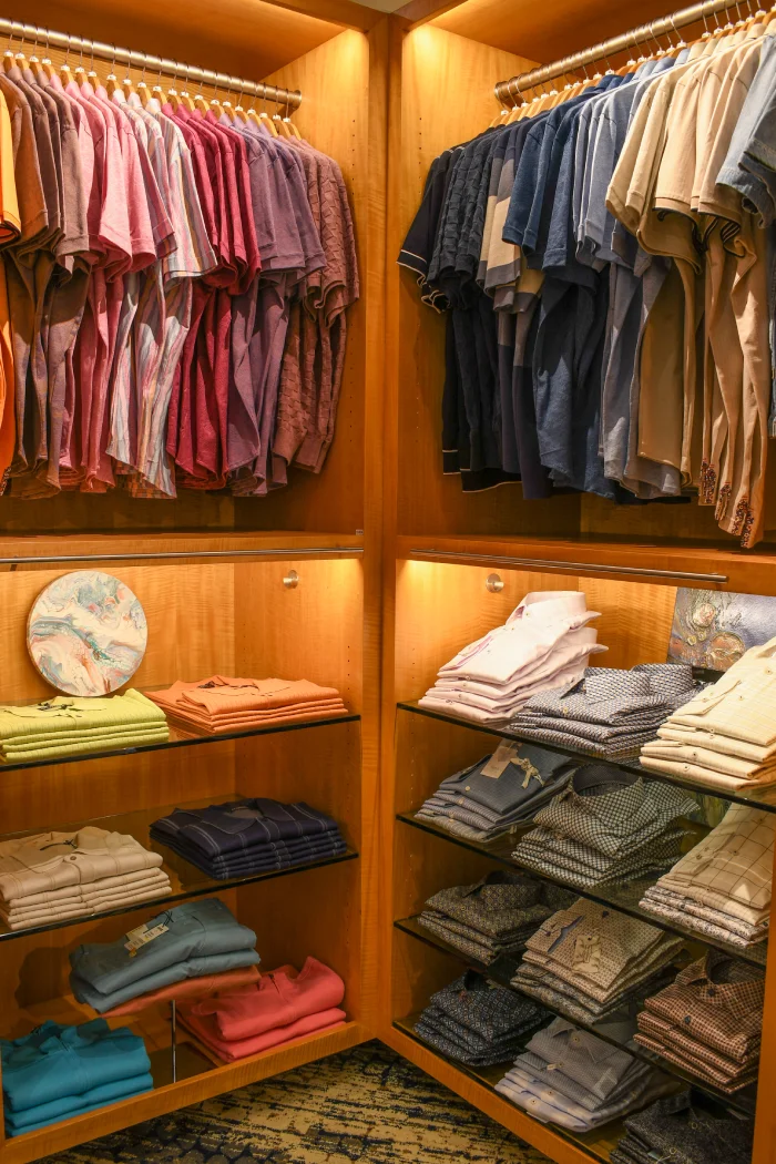 An assortment of casual mens shirts displayed on hangers and neatly folded on shelves.