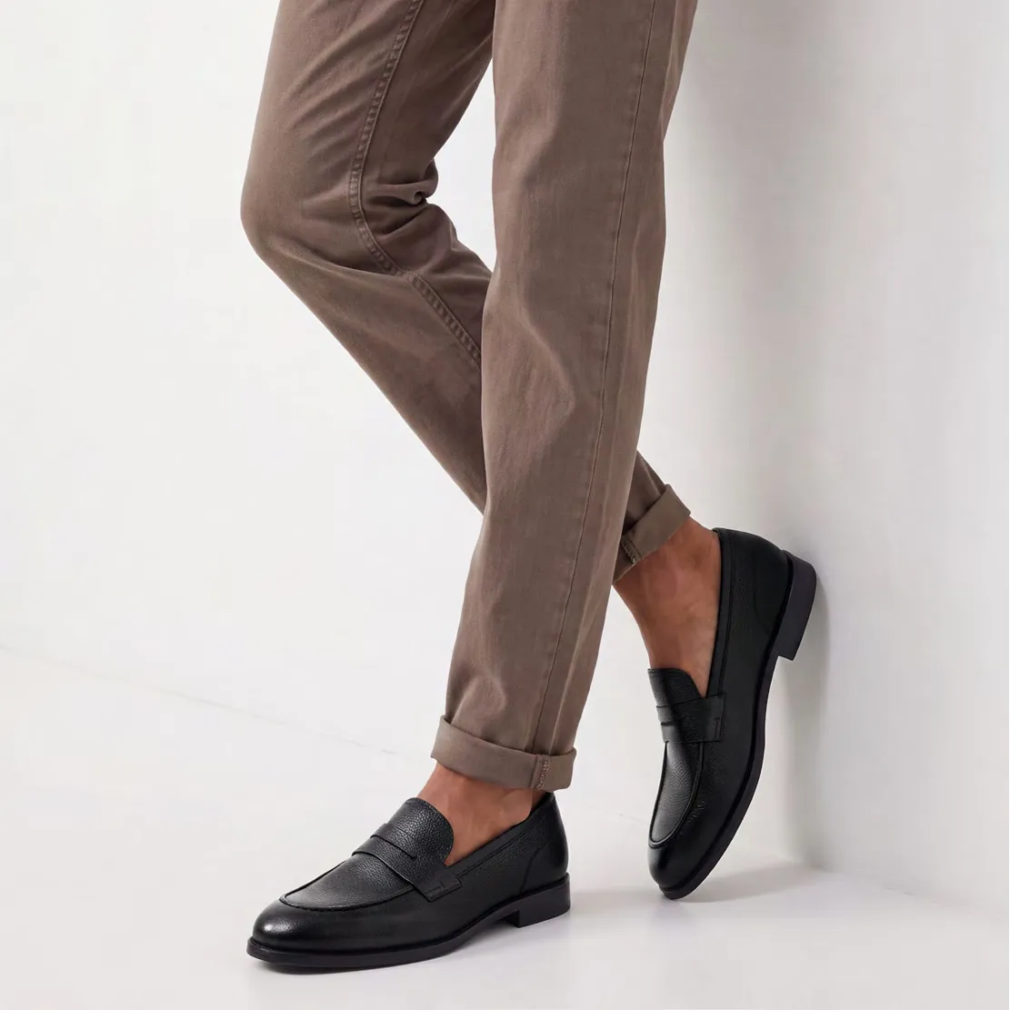 Man wearing black leather loafers with tailored trousers