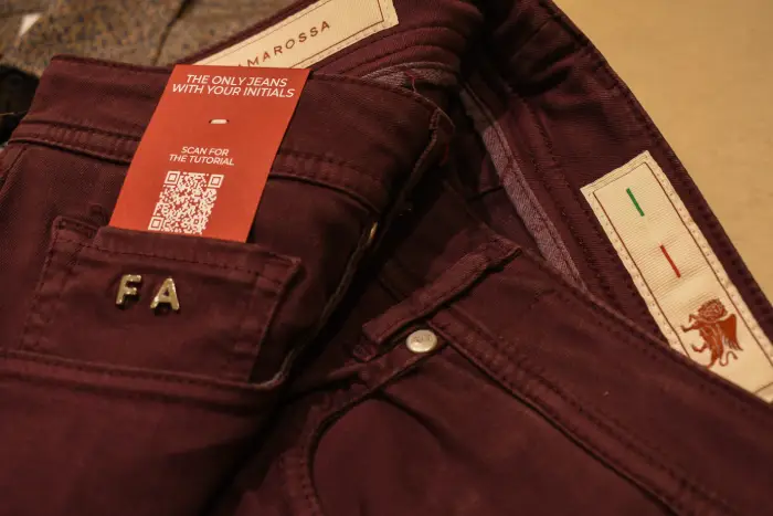 Close-up of burgundy men’s jeans with Alberto Ceramica branding and FA initials.